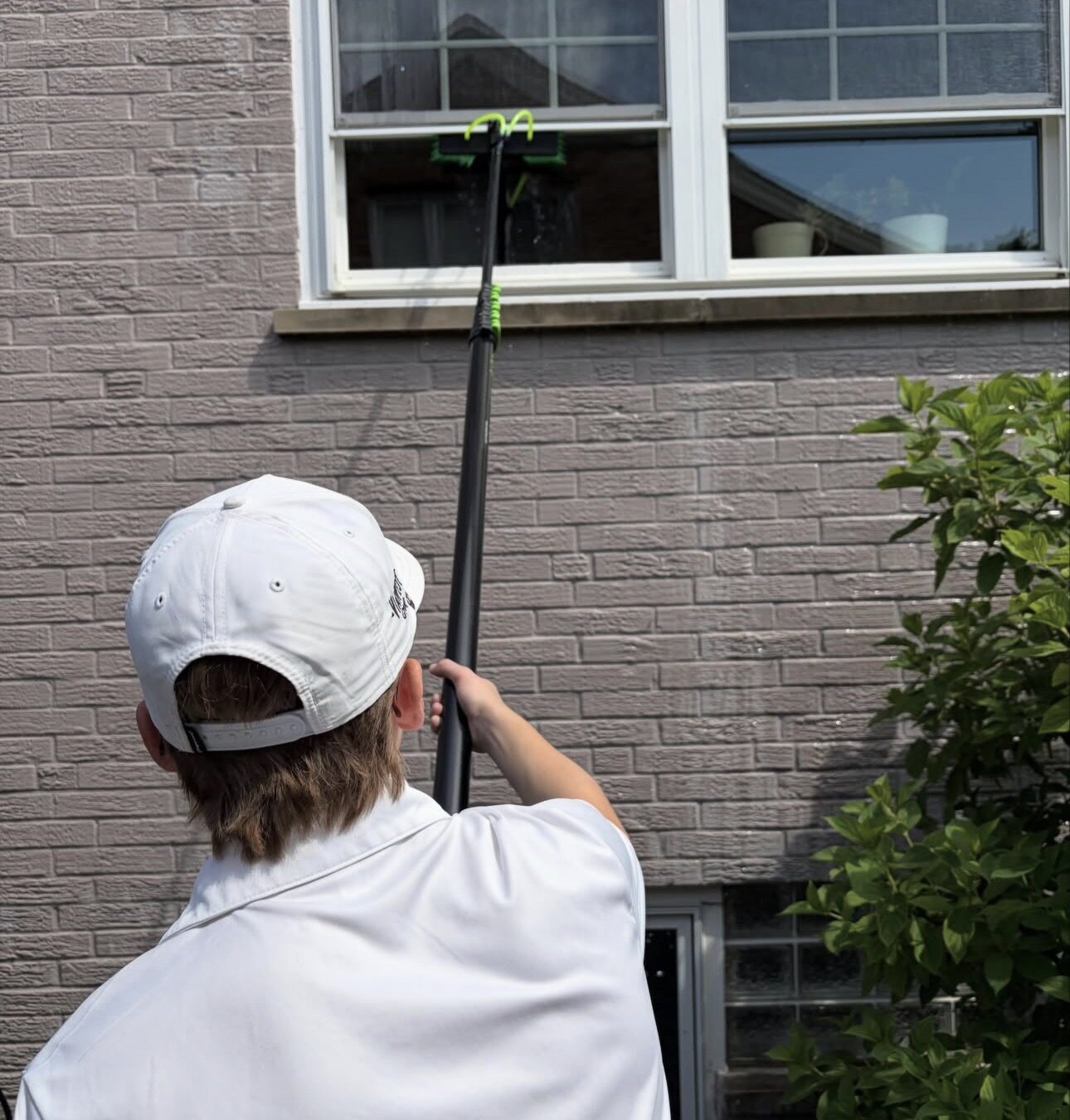 Water-fed pole cleaning windows on a two-story house