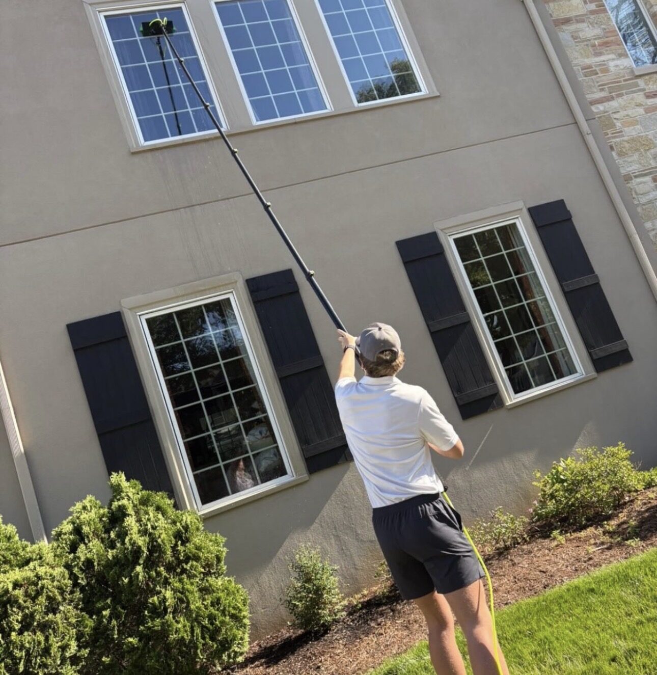 Ultra View using a 30-foot water-fed pole to clean upstairs windows on a brick home