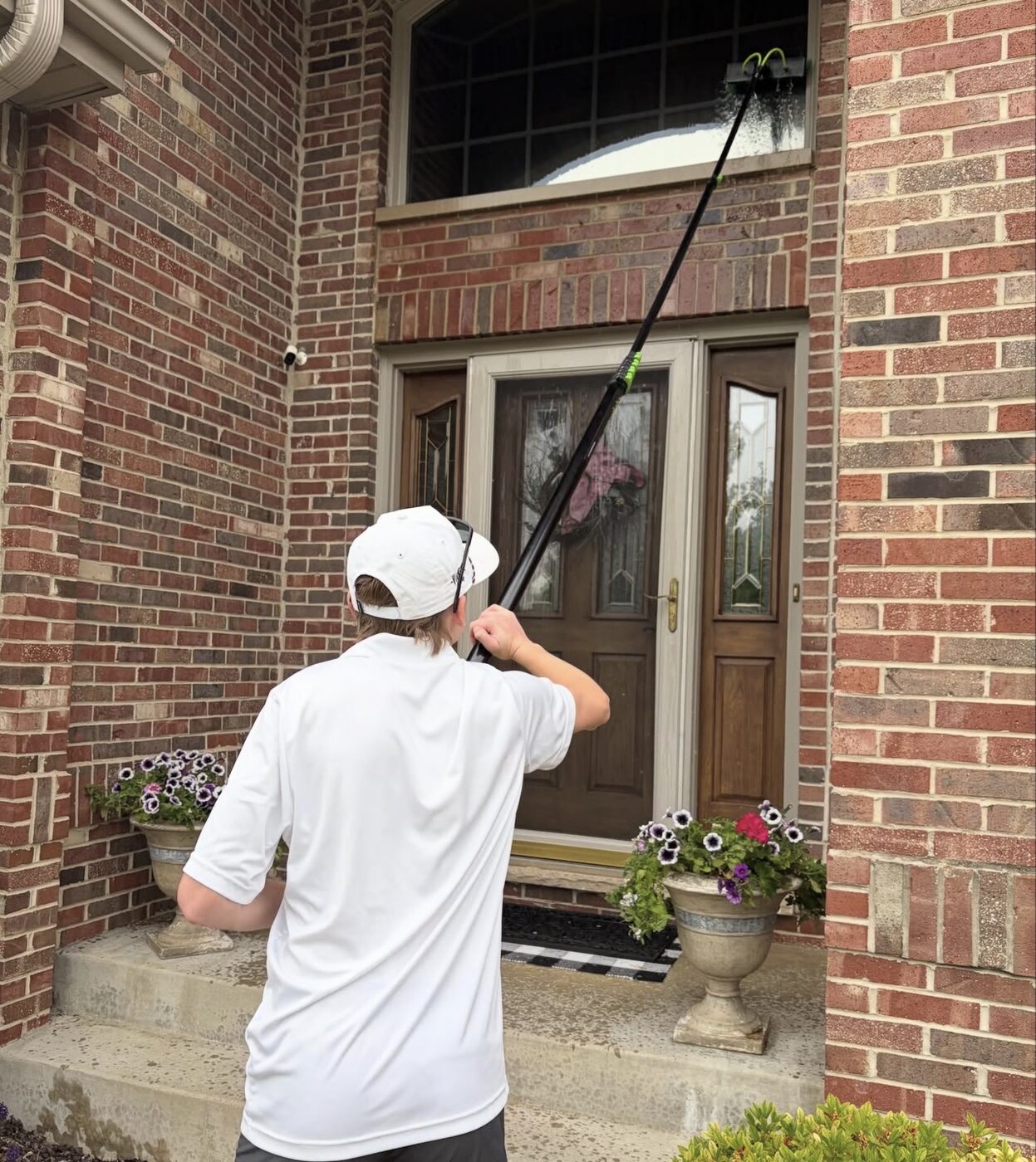 Cleaning upstairs windows on a brick home with a water-fed pole